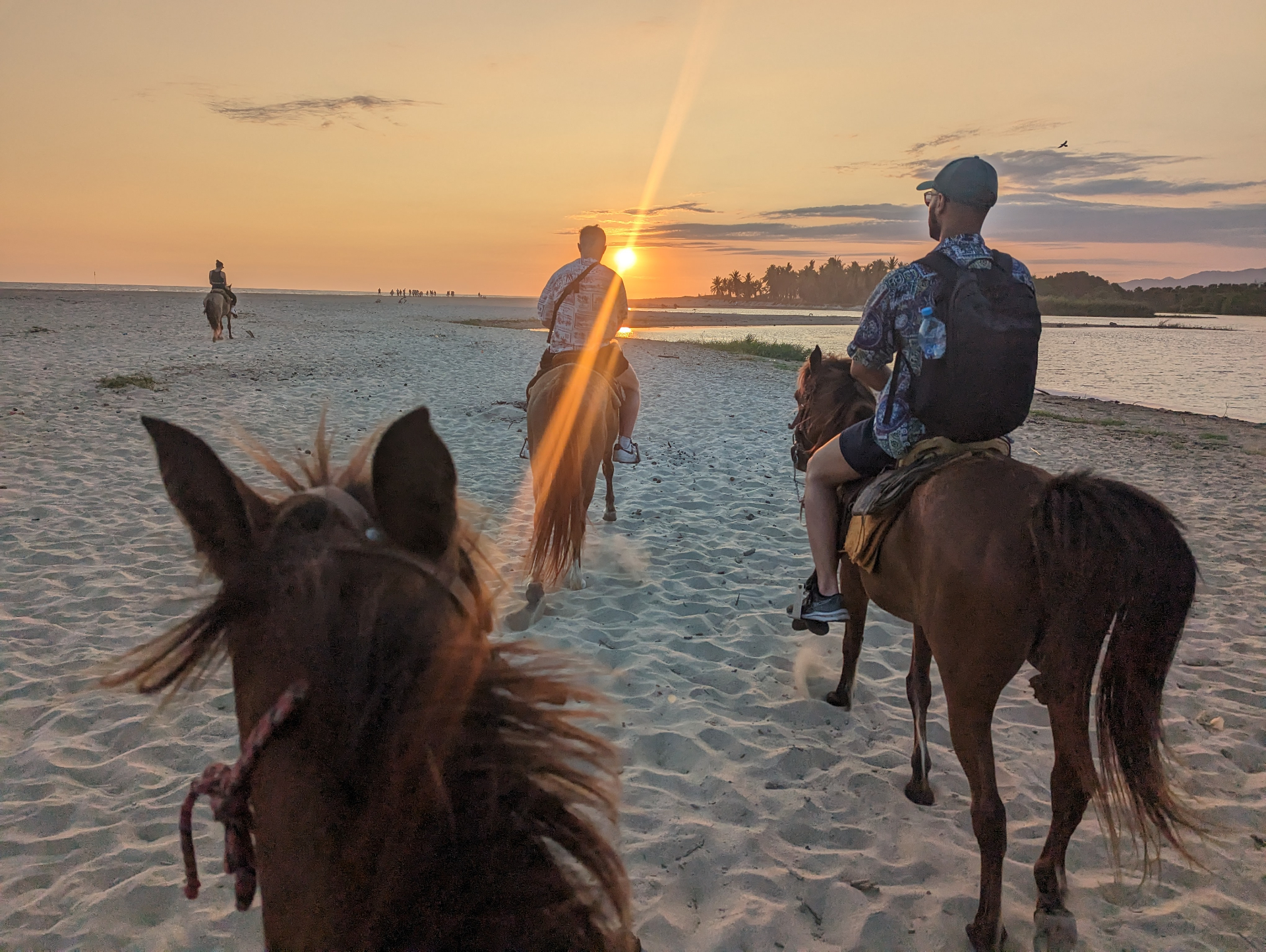 Horseback riders at sunset on sandy beach